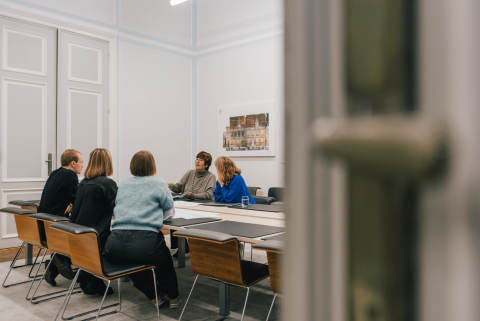 5 collega's rond vergadertafel